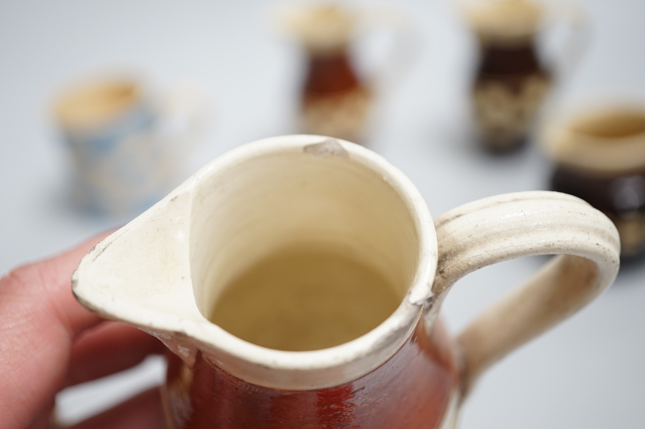 Eight 19th century slip-decorated creamware chequer-pattern jugs and mugs, tallest 10cm